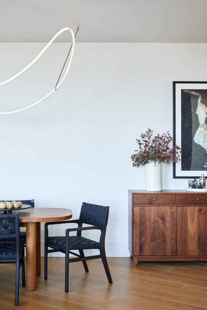 Pill shaped wooden dining table and black chairs with custom bar area