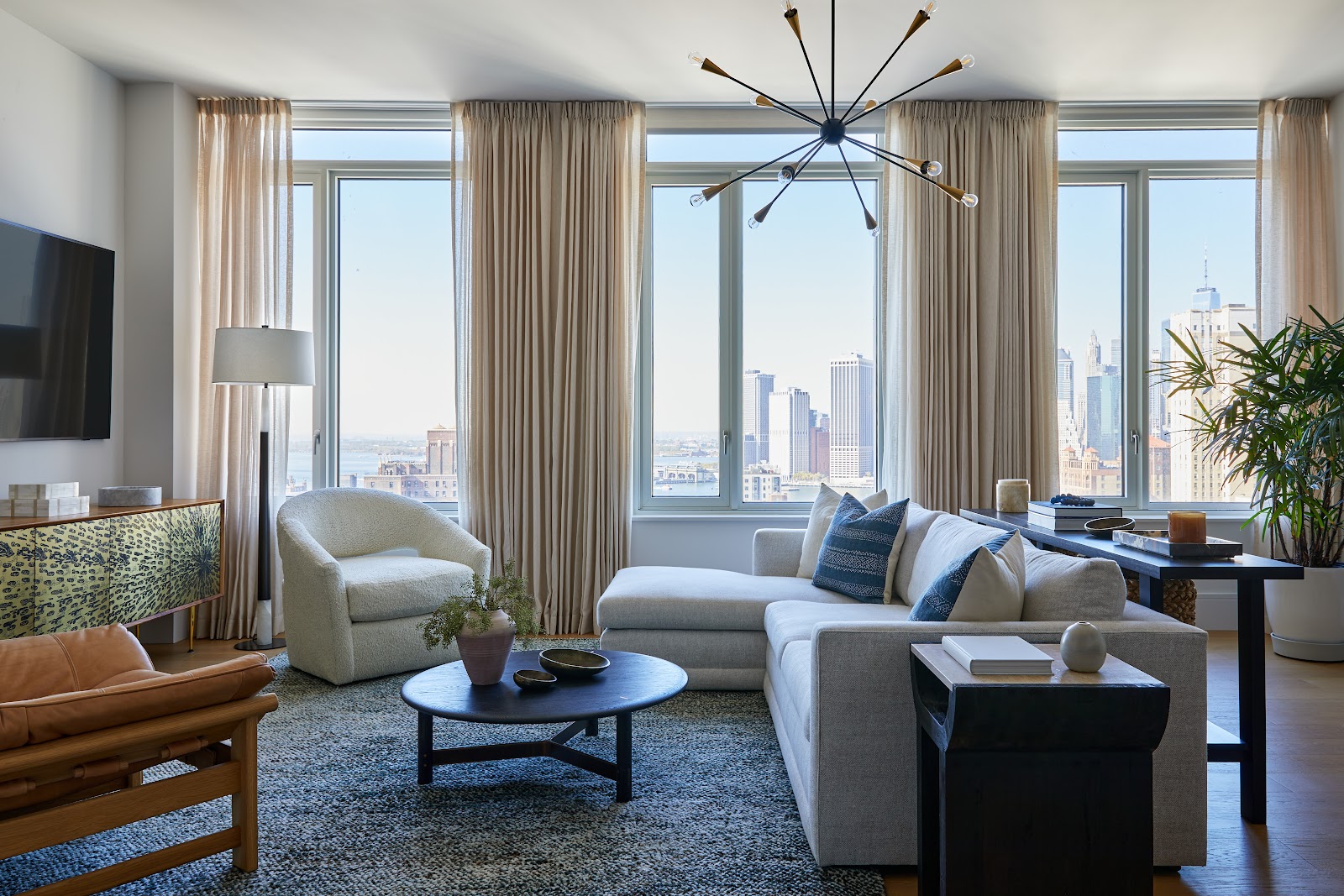 Living room area with abstract ceiling lights, large windows and natural tones.