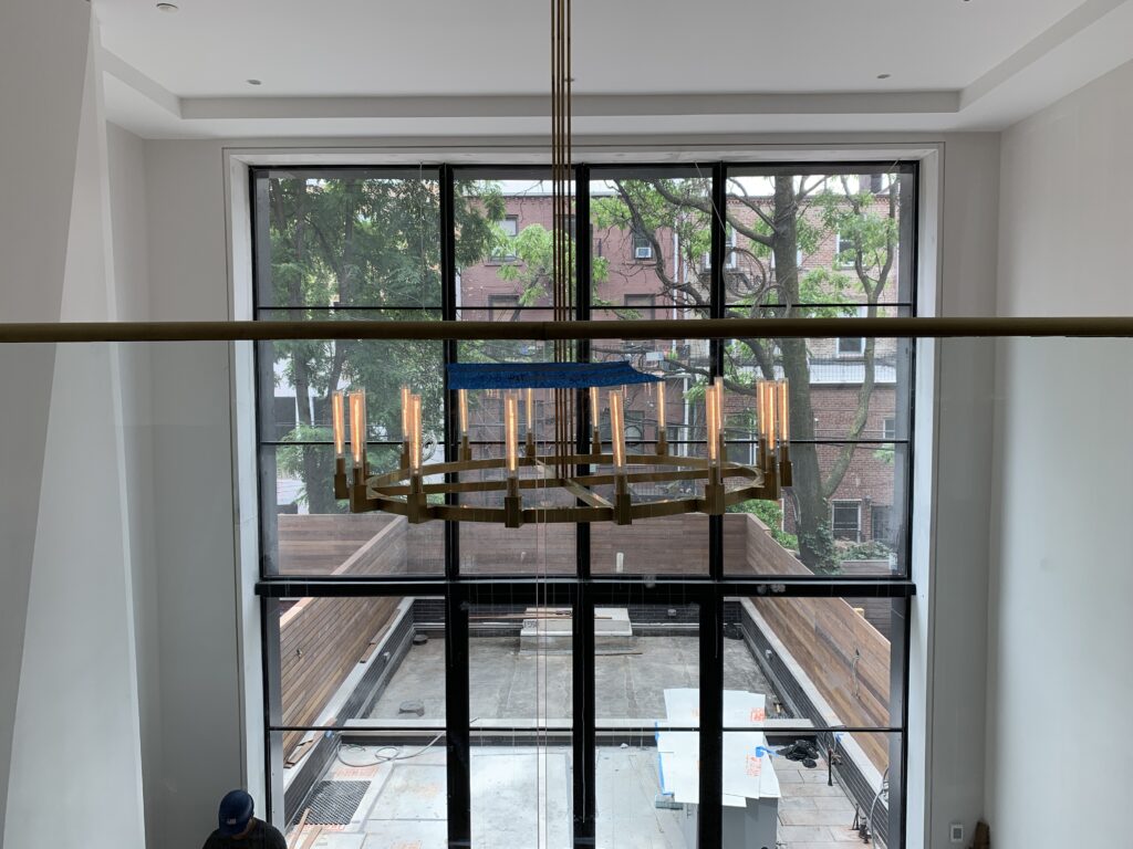 Sunlit living room with large windows and modern design by Atelier Roux for a family-friendly home.